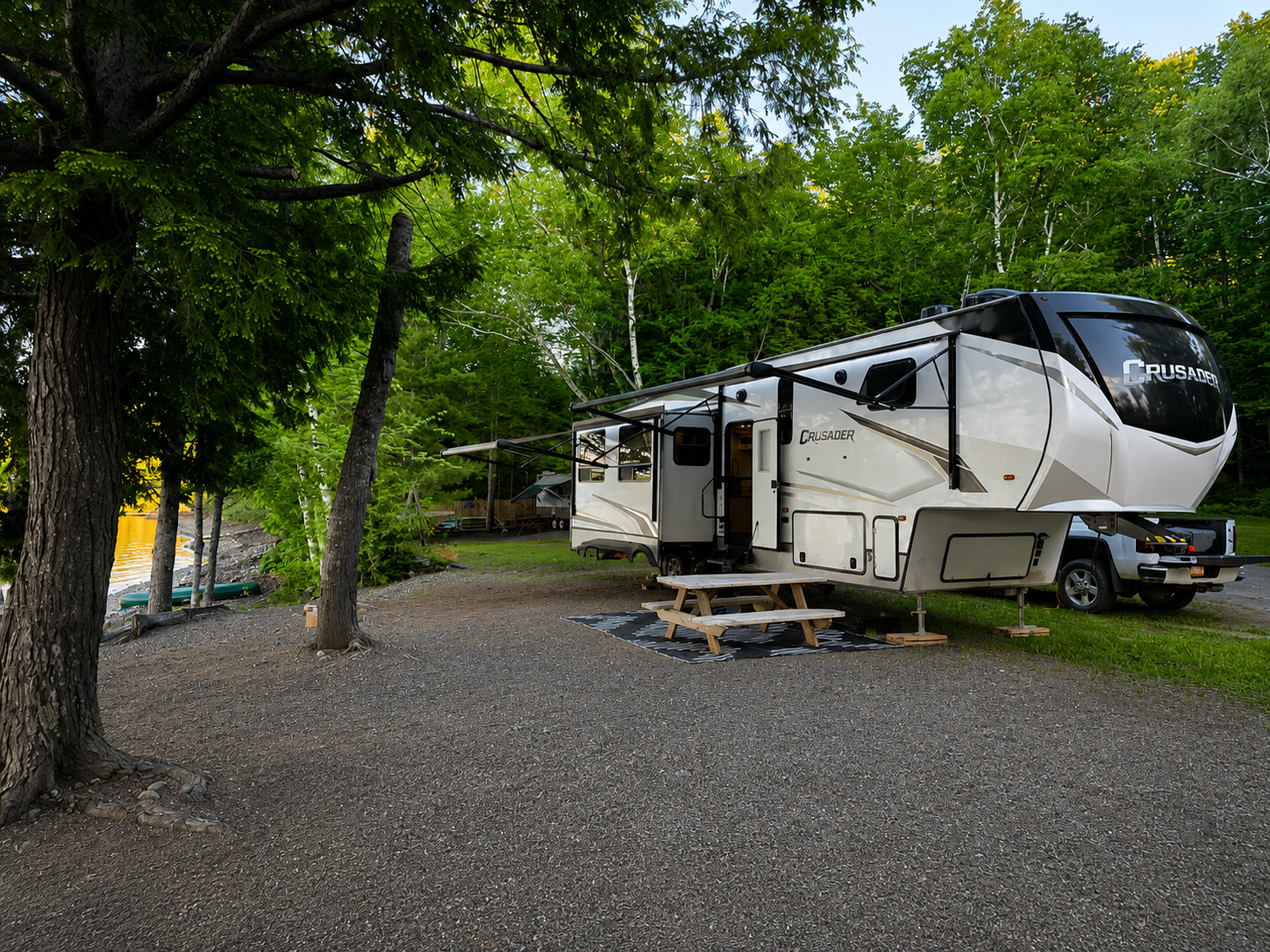 Noreast Nomad fifth-wheel RV set up at a lakeside campsite in Maine at night